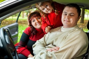 Married couple and  little girl sit in car in park