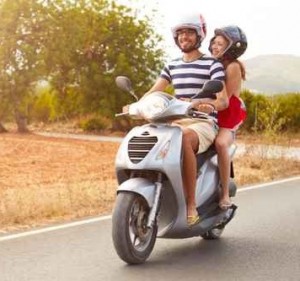 Young Couple Riding Motor Scooter Along Country Road