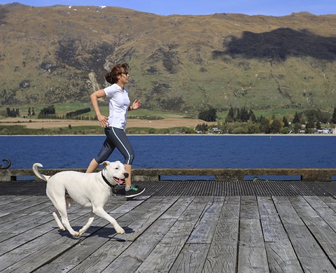 Young adult woman running with her dog