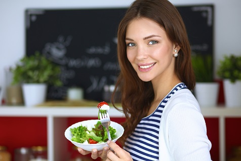 Young woman eating salad and holding a mixed salad