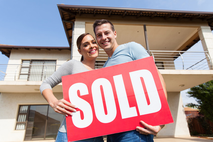 young couple outdoors with sold sign