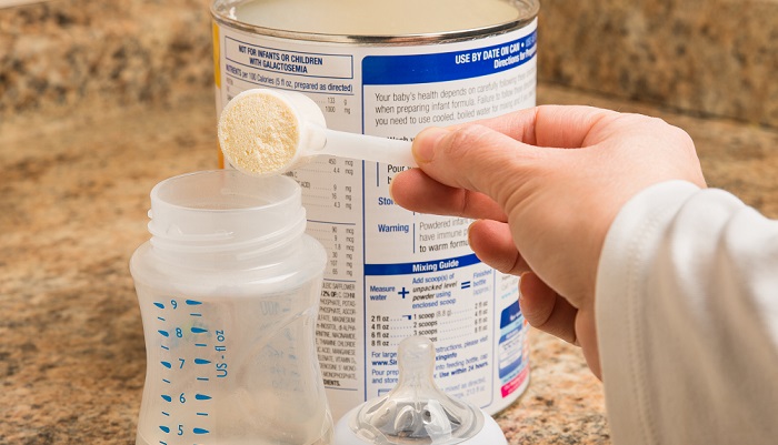 Mother preparing baby formula for infant